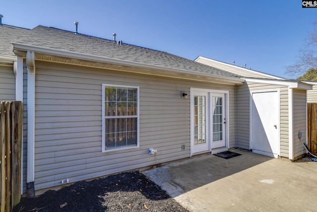 back of property with a shingled roof, an outbuilding, a patio area, and fence