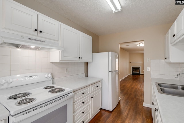 kitchen featuring white appliances, dark wood-style flooring, light countertops, under cabinet range hood, and a sink