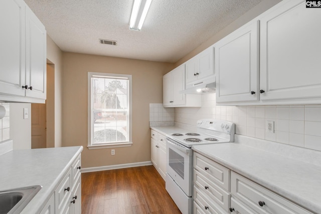 kitchen with dark wood finished floors, white range with electric cooktop, visible vents, backsplash, and under cabinet range hood