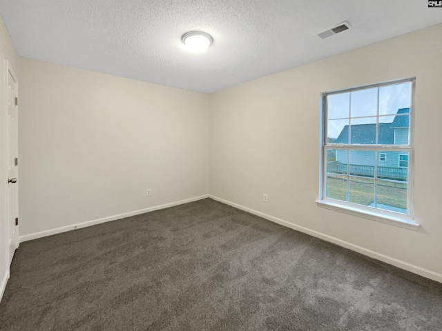 unfurnished room featuring a textured ceiling, dark carpet, visible vents, and baseboards