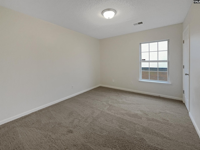 carpeted empty room with baseboards, visible vents, and a textured ceiling