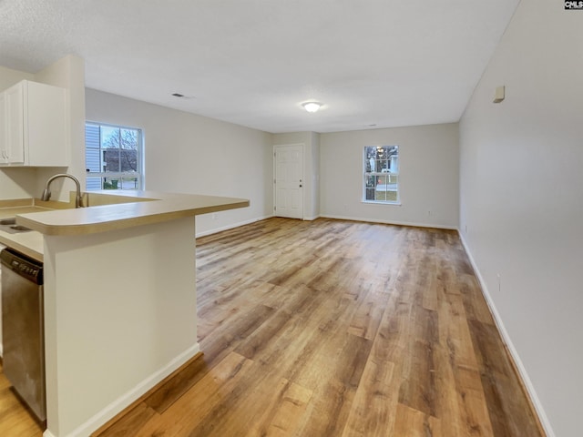 kitchen featuring plenty of natural light, white cabinetry, dishwasher, and a sink