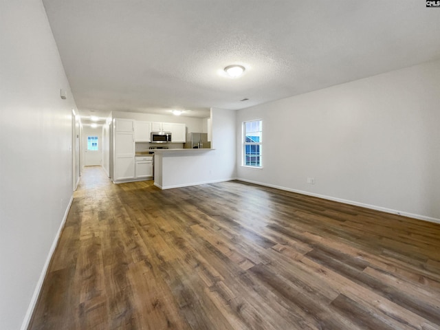 unfurnished living room featuring dark wood-style floors, a textured ceiling, and baseboards