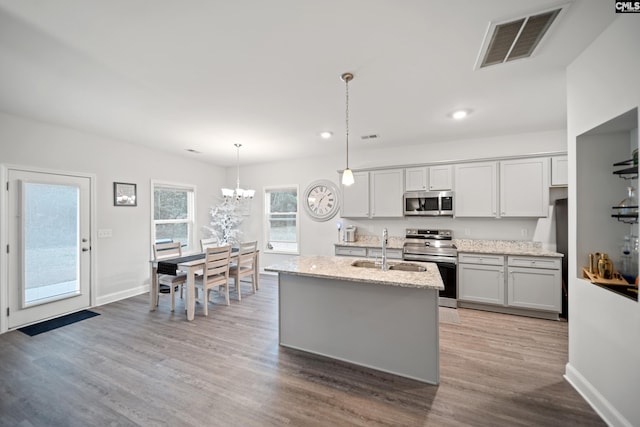 kitchen featuring light wood finished floors, stainless steel appliances, visible vents, a sink, and light stone countertops