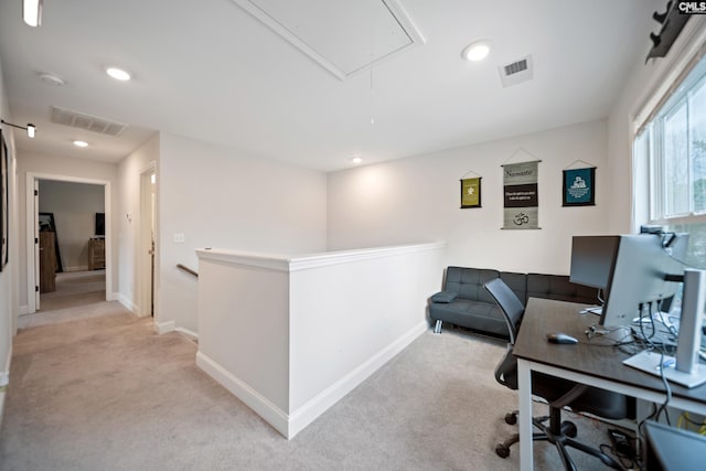 office featuring visible vents, attic access, and light colored carpet