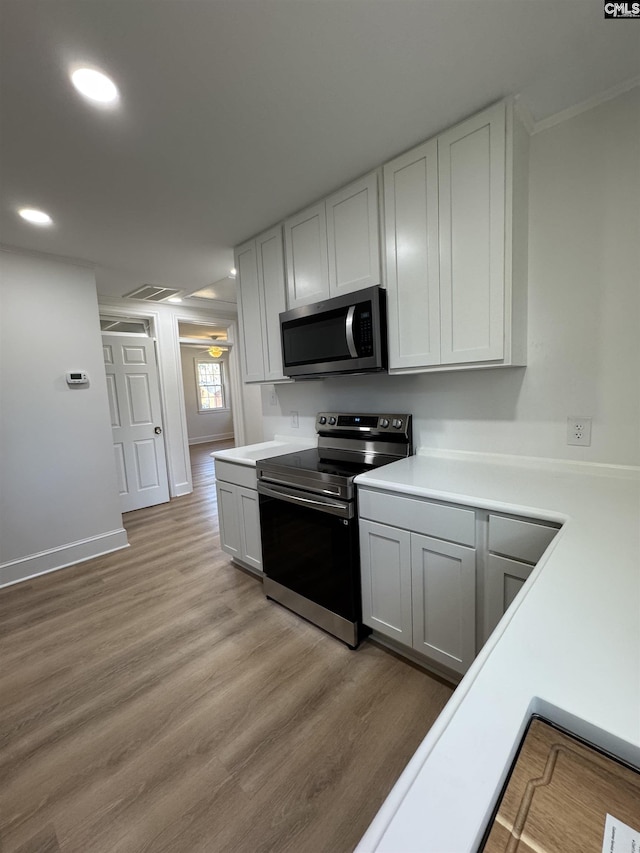 kitchen featuring baseboards, appliances with stainless steel finishes, light countertops, light wood-type flooring, and recessed lighting