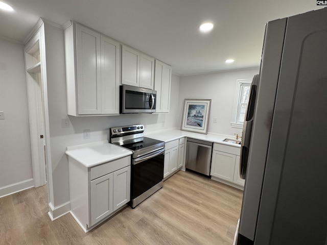 kitchen with stainless steel appliances, light countertops, light wood-type flooring, a sink, and recessed lighting