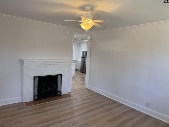 unfurnished living room featuring a ceiling fan, a fireplace, ornamental molding, and wood finished floors