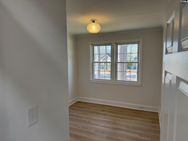 unfurnished room with ornamental molding, baseboards, and wood finished floors