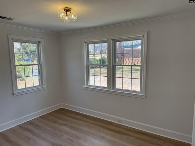 unfurnished room with baseboards, dark wood-style floors, visible vents, and a healthy amount of sunlight