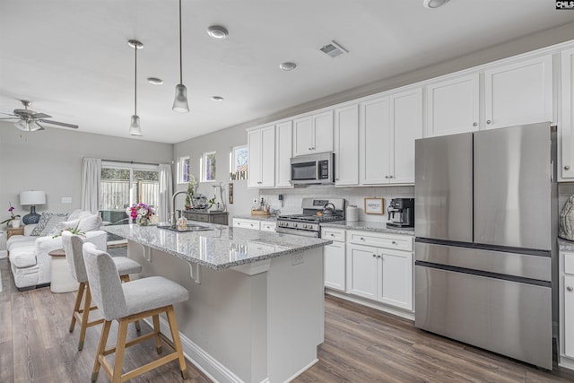 kitchen featuring tasteful backsplash, white cabinets, dark wood-style floors, appliances with stainless steel finishes, and a sink