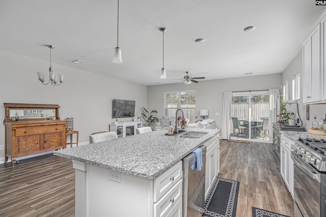 kitchen featuring light stone counters, dark wood-type flooring, a sink, white cabinets, and appliances with stainless steel finishes