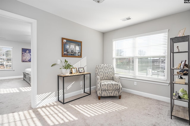 living area featuring carpet floors, a healthy amount of sunlight, visible vents, and baseboards