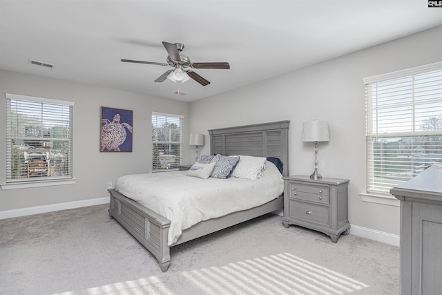 bedroom featuring a ceiling fan, visible vents, light carpet, and baseboards