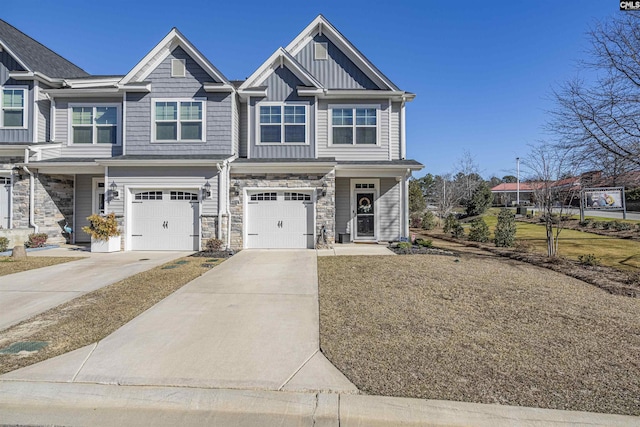 view of front of home with board and batten siding, stone siding, an attached garage, and concrete driveway