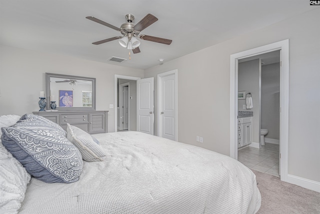 bedroom featuring light carpet, a ceiling fan, visible vents, baseboards, and ensuite bath