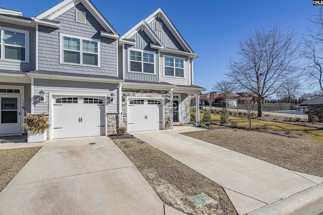 view of front of property with driveway, stone siding, a garage, and board and batten siding