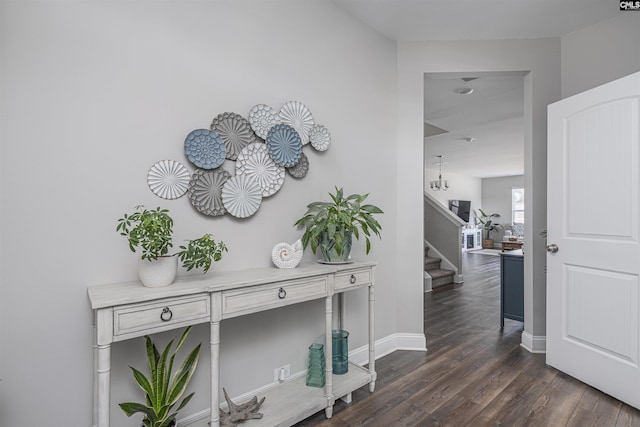 hall featuring dark wood-type flooring, baseboards, and stairs