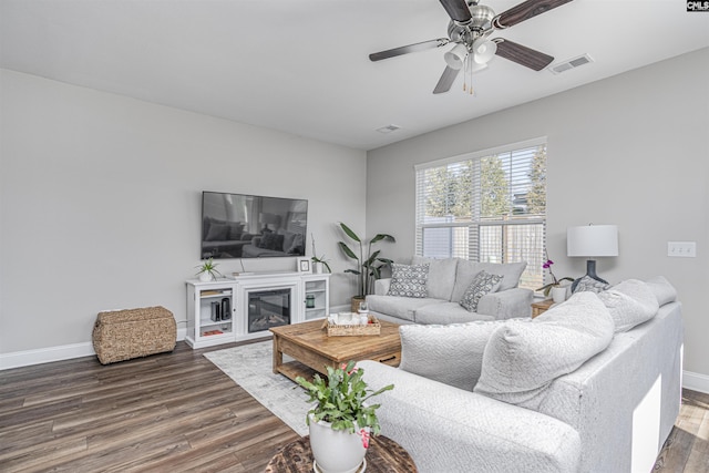 living room featuring a ceiling fan, baseboards, visible vents, and wood finished floors