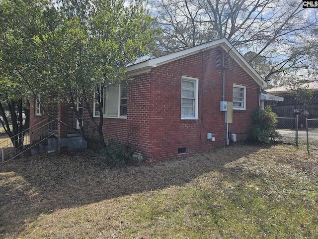 view of home's exterior with crawl space, brick siding, and fence