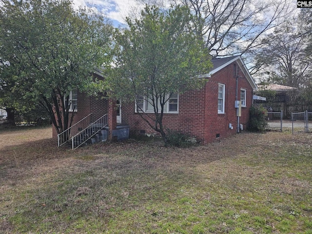 view of home's exterior featuring brick siding, crawl space, fence, and a lawn