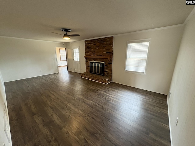 unfurnished living room featuring ornamental molding, a brick fireplace, dark wood finished floors, and ceiling fan