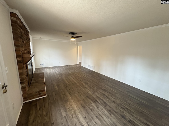 unfurnished living room with visible vents, ceiling fan, wood finished floors, crown molding, and a brick fireplace