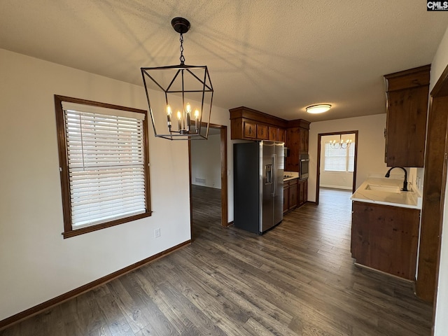 kitchen with appliances with stainless steel finishes, dark wood finished floors, a notable chandelier, and a sink