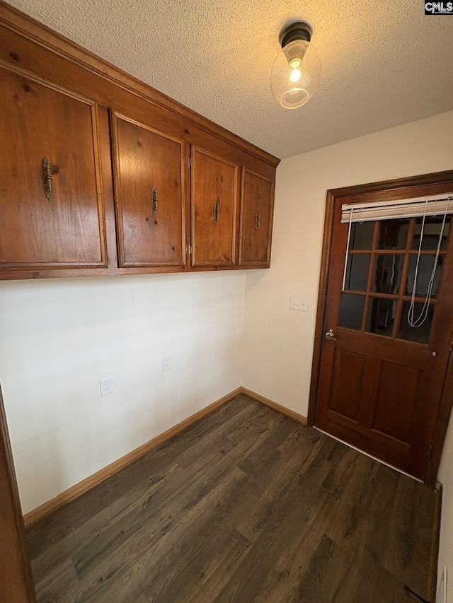 laundry area featuring dark wood-style floors, baseboards, and a textured ceiling