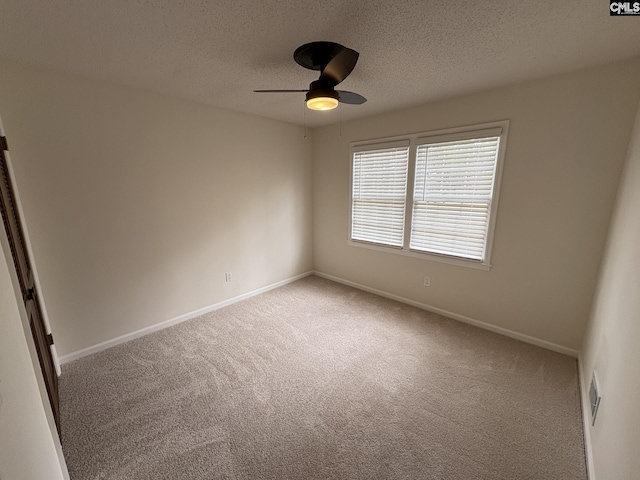 empty room with a textured ceiling, ceiling fan, carpet, and baseboards