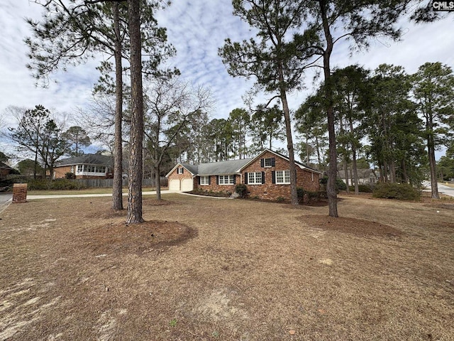 single story home featuring a garage, driveway, and brick siding