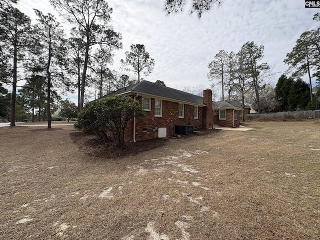 view of home's exterior featuring brick siding, a chimney, and central air condition unit