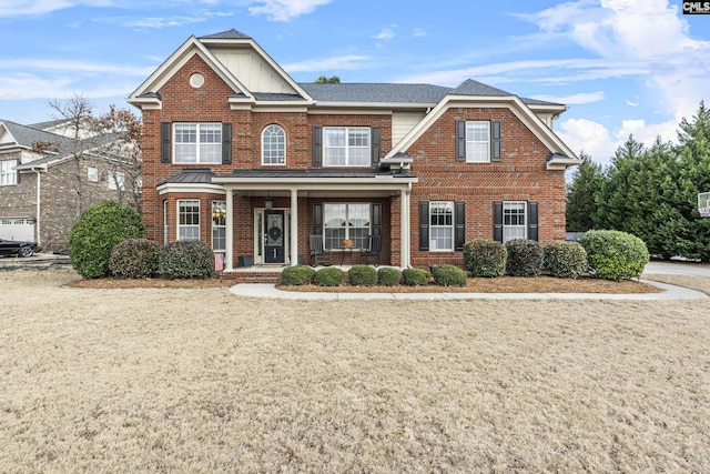 view of front of home with brick siding, a porch, and a front yard