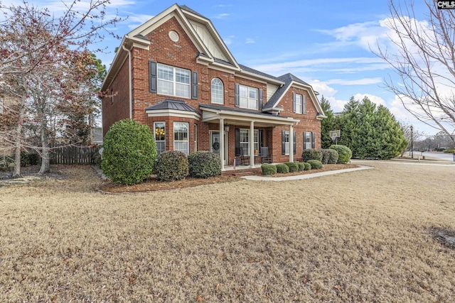 view of front of home with a porch, a front yard, and brick siding