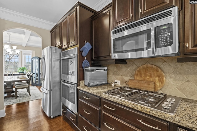 kitchen with dark wood-style flooring, beam ceiling, decorative backsplash, appliances with stainless steel finishes, and ornamental molding