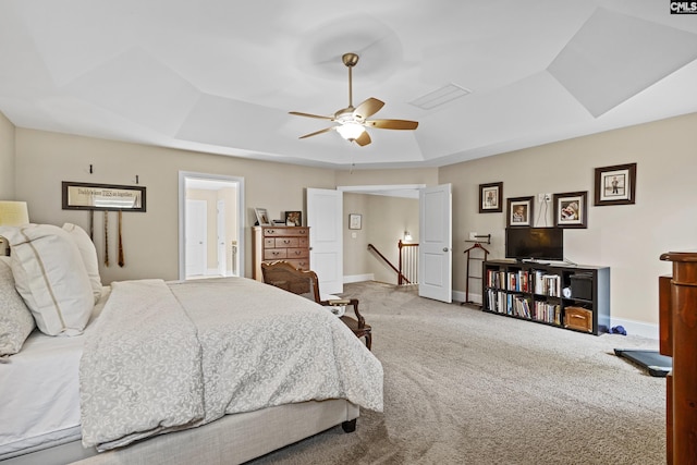 carpeted bedroom featuring a raised ceiling, ceiling fan, and baseboards