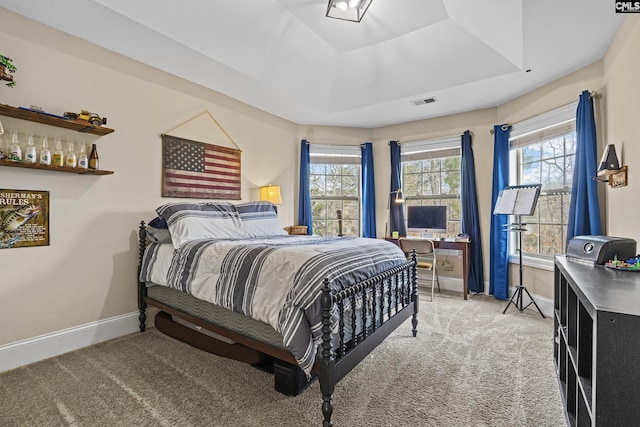 bedroom featuring light carpet, baseboards, visible vents, and a tray ceiling