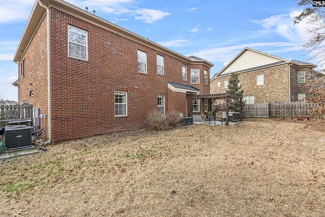 rear view of house with brick siding, a patio area, cooling unit, and a pergola