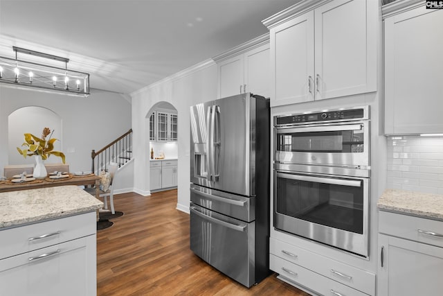 kitchen with stainless steel appliances, backsplash, dark wood-type flooring, ornamental molding, and light stone countertops