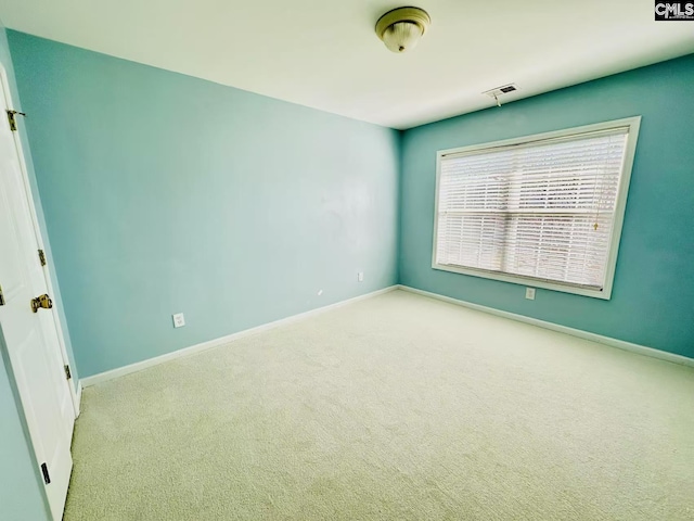 carpeted spare room featuring visible vents and baseboards