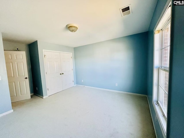 empty room with carpet, visible vents, and baseboards