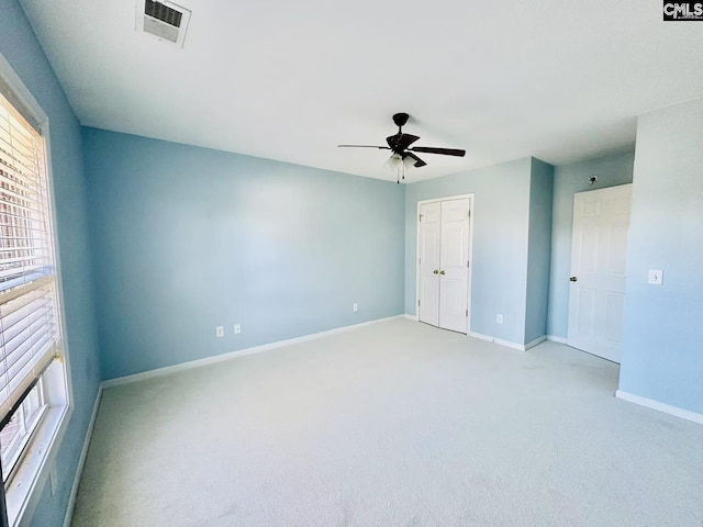 unfurnished bedroom featuring a closet, light colored carpet, visible vents, a ceiling fan, and baseboards