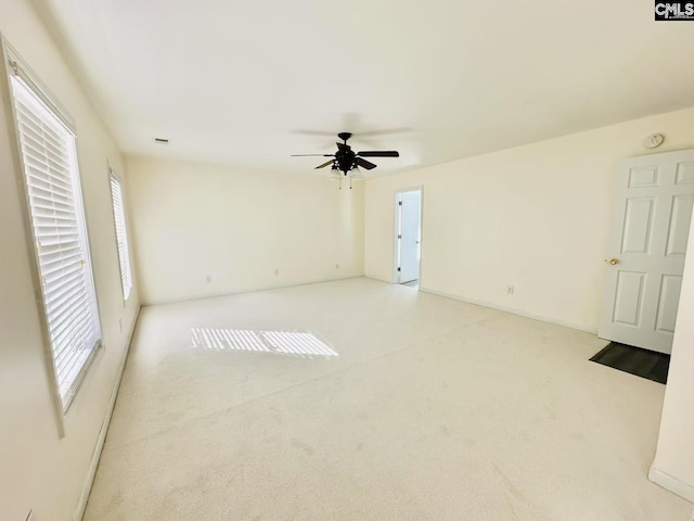 spare room featuring visible vents, a ceiling fan, and light colored carpet