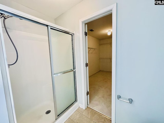 full bathroom with a spacious closet, a shower stall, and visible vents