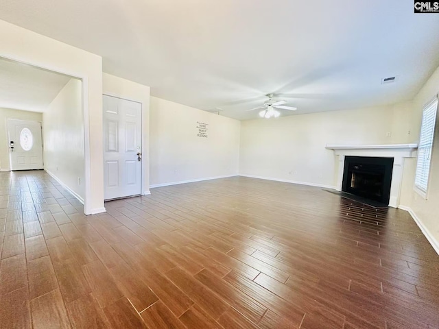 unfurnished living room featuring a ceiling fan, a fireplace with flush hearth, visible vents, and wood finished floors