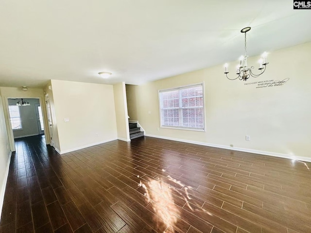 unfurnished living room with baseboards, stairway, dark wood-style flooring, and a notable chandelier