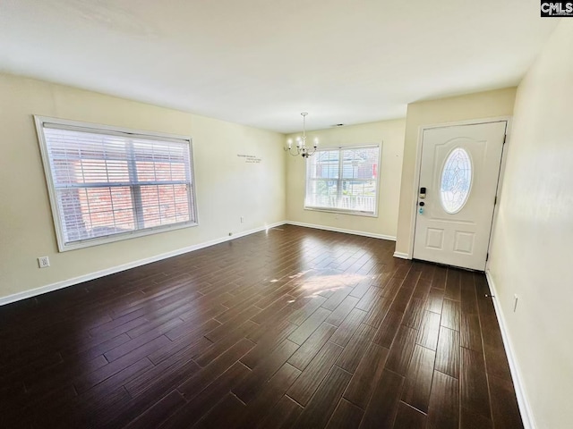 entryway featuring baseboards, dark wood-type flooring, and an inviting chandelier