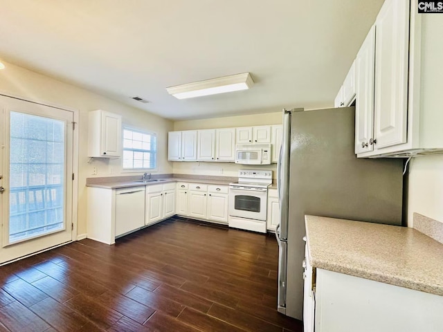 kitchen with white appliances, a sink, visible vents, white cabinets, and dark wood-style floors