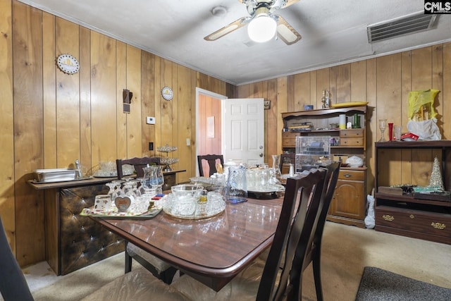 dining room with carpet floors, wood walls, visible vents, and a ceiling fan