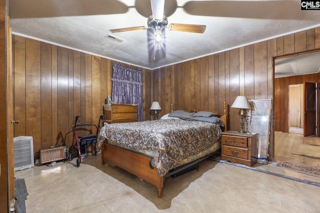 bedroom with ornamental molding, visible vents, wood walls, and ceiling fan